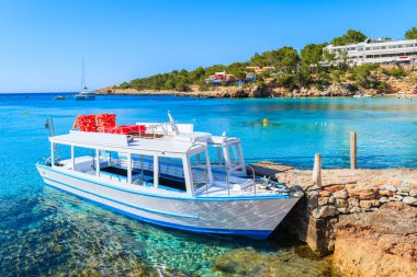 İspanya 'nın İbiza adasındaki Cala Portinatx Körfezi' nde demirleyen turistler için beyaz ve mavi feribot.