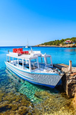 İspanya 'nın İbiza adasındaki Cala Portinatx Körfezi' nde demirleyen turistler için beyaz ve mavi feribot.