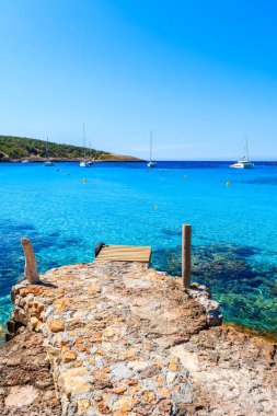 İspanya 'nın Ibiza Adası, Cala Portinatx' ın güzel körfezinde iskele ve gök mavisi deniz suyu.