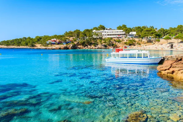 İspanya 'nın İbiza adasındaki Cala Portinatx Körfezi' nde demirleyen turistler için beyaz ve mavi feribot.