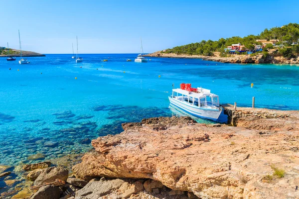 İspanya 'nın İbiza adasındaki Cala Portinatx Körfezi' nde demirleyen turistler için beyaz ve mavi feribot.