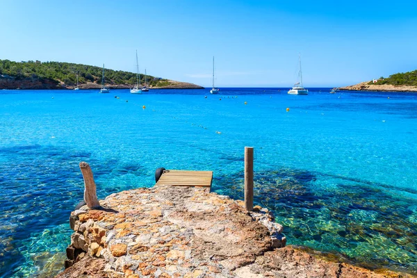 İspanya 'nın Ibiza Adası, Cala Portinatx' ın güzel körfezinde iskele ve gök mavisi deniz suyu.