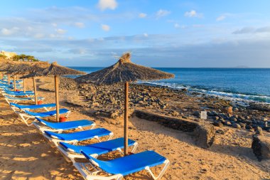 Satır günbatımı zaman Playa Blanca Plajda şemsiye ve şezlong