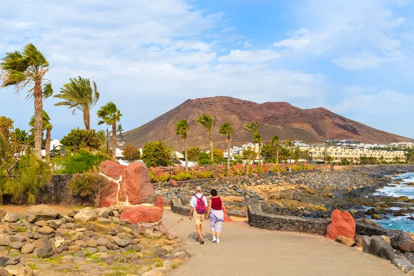 Casal de turistas caminhando no calçadão costeiro ao longo do oceano em Playa Blanca — Fotografia de Stock