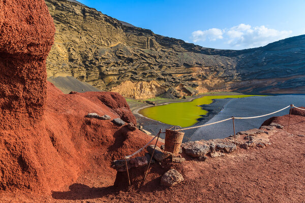 Red lava rocks and green water of Lago Verde, El Golfo