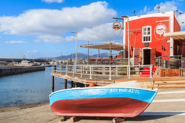 Colorful fishing boat in front of red restaurant building