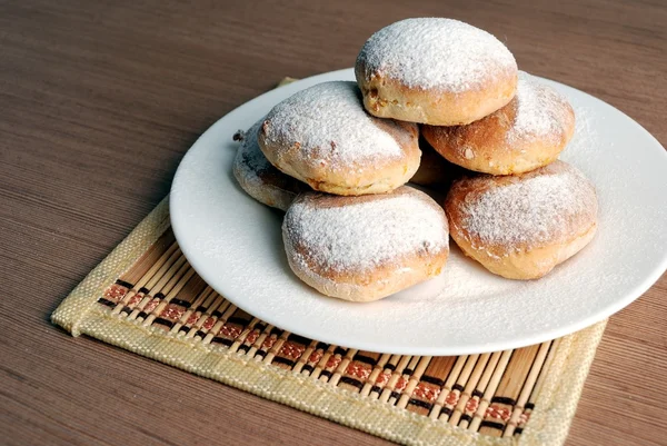 Bun with powdered sugar on a wooden table — Stock Photo, Image