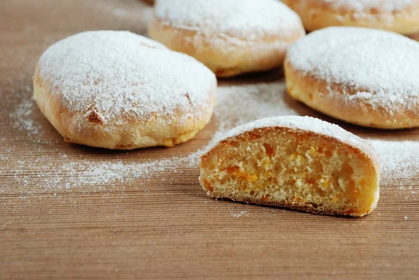 Bun with powdered sugar on a wooden table — Stock Photo, Image