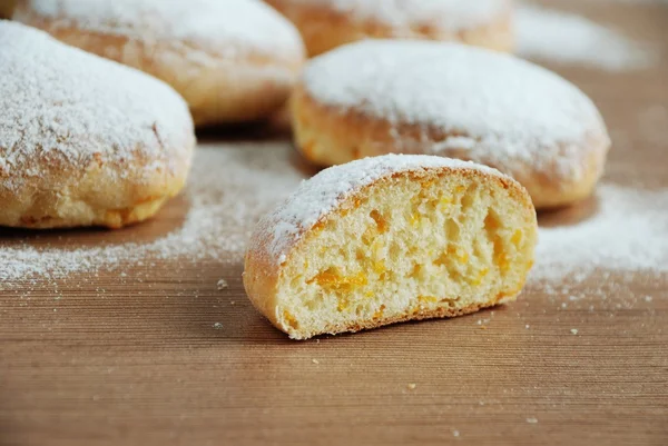 Bun with powdered sugar on a wooden table — Stock Photo, Image