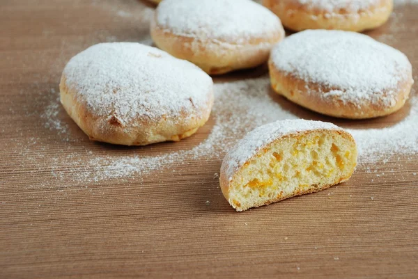 Bun with powdered sugar on a wooden table — Stock Photo, Image