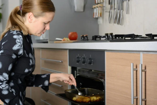 Woman cooks potatoes in the oven — Stock Photo, Image