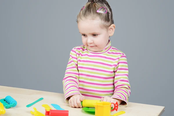 Menina brincando com utensílios de mesa de plástico — Fotografia de Stock