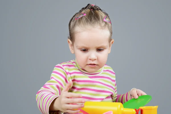 Menina brincando com utensílios de mesa de plástico — Fotografia de Stock