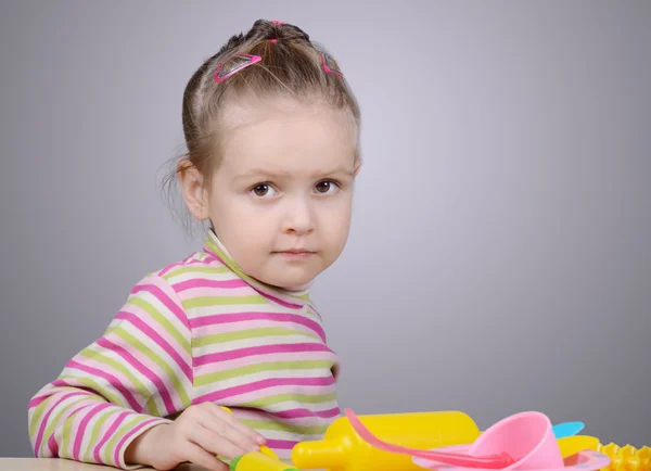 Girl playing with plastic tableware — Stock Photo, Image