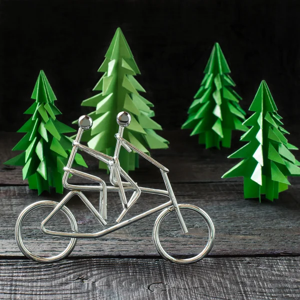 Figuras metálicas ciclistas e origami de abeto — Fotografia de Stock