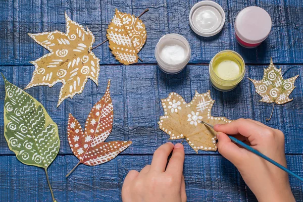 Девушка рисует узоры сухих осенних листьев — стоковое фото