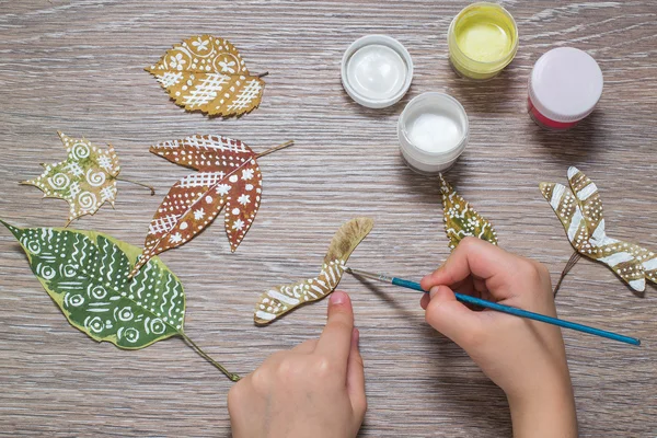 Girl paints patterns of dry autumn leaves