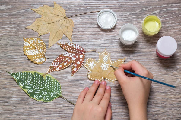 Девушка рисует узоры сухих осенних листьев — стоковое фото