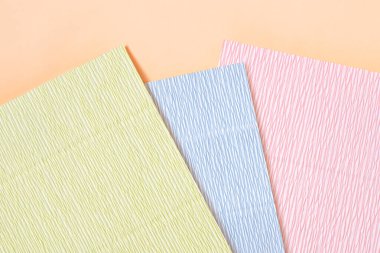 Şeftali rengi kağıt üzerine üç sayfa renkli kıvrımlı kağıt. Krep kağıdı dokusu. Kağıt kırışıklıkları, dalgalı yüzey