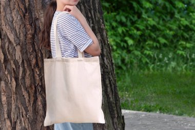 Boş, yeniden kullanılabilir tuval çanta modeli. Doğal tuval çevre dostu alışveriş torbası kızın omzunda. Tasarım veya markanın sunumu için model