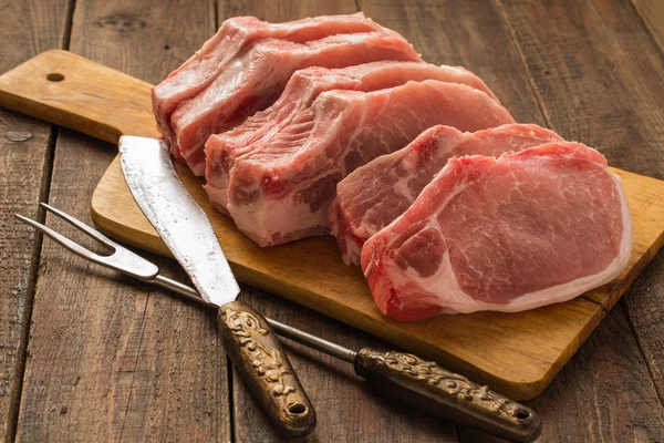 Steaks de porc cru sur une planche à découper — Photo