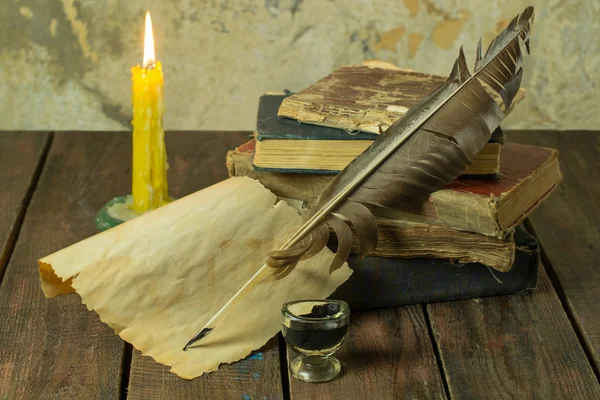 Старые книги, свечи и перья с чернилами — стоковое фото