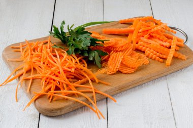 Sliced carrots and parsley on a cutting board 