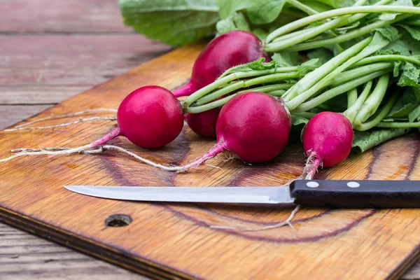 Un bouquet de radis frais sur une vieille planche à découper — Photo