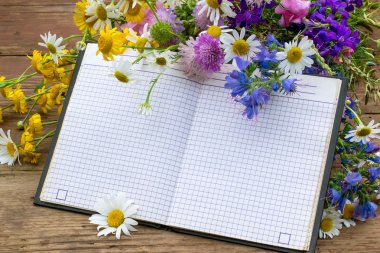 Kayıt için bir not defteri ve kır çiçekleri buketi 