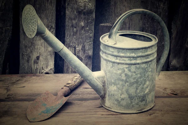 Старые садовые инструменты: банка для полива и лопата — стоковое фото