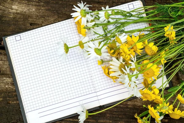 Bouquet of white and yellow daisies and a notebook for recording — Stock Photo, Image