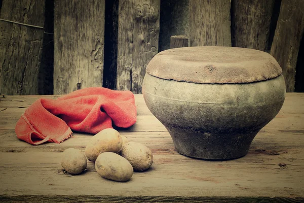 Древний чугунный горшок и картофель на старом столе в саду — стоковое фото