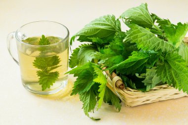 Nettle leaves in a basket and an infusion in a mug 