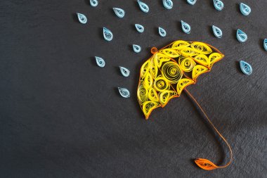 Umbrella and raindrops on the quilling technique on slate board 
