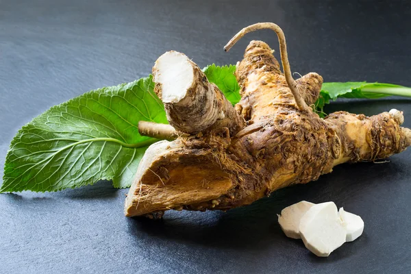 Washed horseradish root, peeled slices and green leaf — Stock Photo, Image