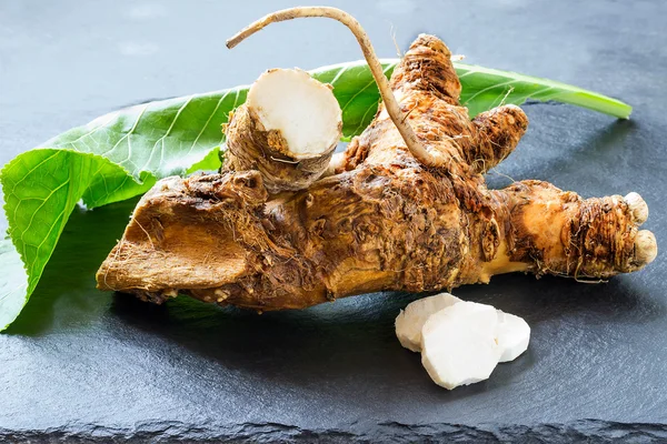 Roots and leaves of horseradish on a slate board — Stock Photo, Image