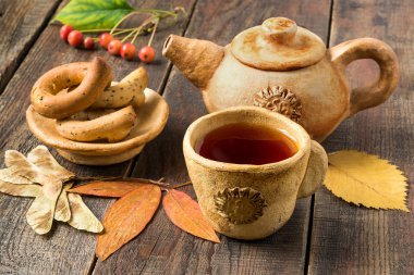 Autumn Tea Party: Hot tea in clay tableware and autumn leaves 