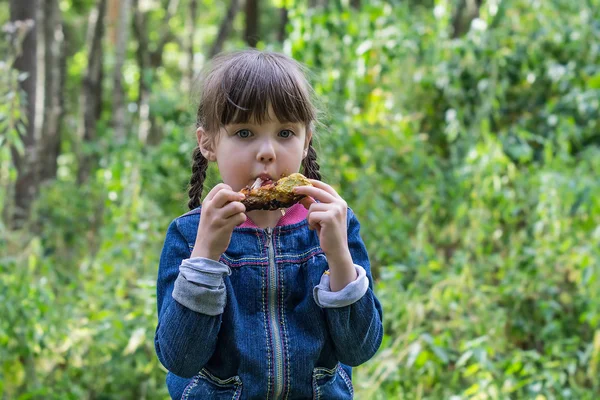 Menina no piquenique comendo com perna de frango gostoso — Fotografia de Stock