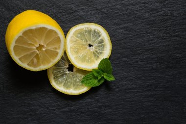 Half of lemon, slices and mint leaves on a slate board