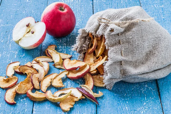 Сушеные яблоки в льняном пакете и свежие спелые яблоки на столе — стоковое фото