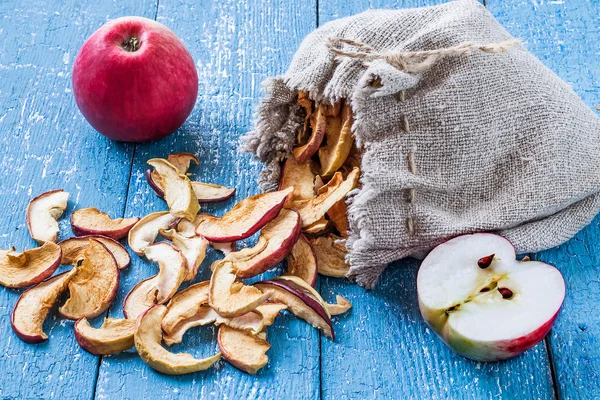 Свежие спелые яблоки на столе и сушеные яблоки в льняном мешке — стоковое фото