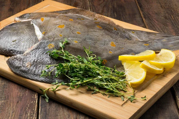 Raw fresh flounder with thyme and lemon on the board — Stock Photo, Image