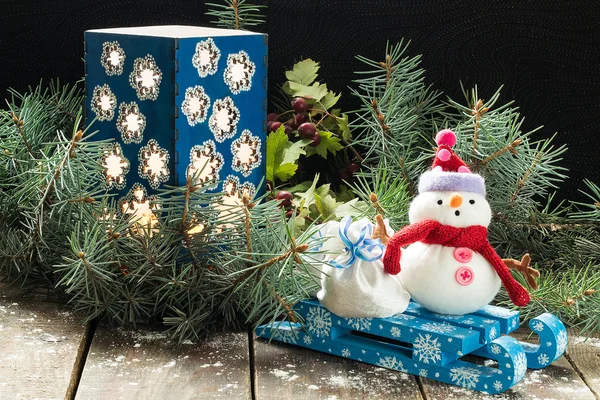 Castiçal nos ramos de abeto e um boneco de neve com saco em um s — Fotografia de Stock