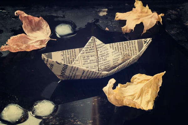 The mood of autumn: the leaves and a paper boat in the puddle. T — Stock Photo, Image