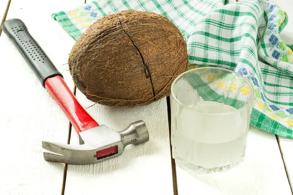 Kokos s crack, kokosová voda, kladivo a ubrousek — Stock fotografie