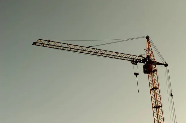 Industrial construction cranes and building silhouettes over sun at sunrise