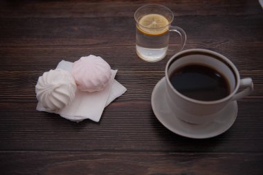 Bir fincan kahve, limonlu su ve lokum, koyu bir ağaca karşı.