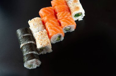 Suşi dürümleri siyah taş üzerine servis edilir. Siyah arka planda.