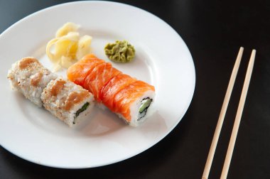 Siyah arka planda beyaz bir tabakta suşi.