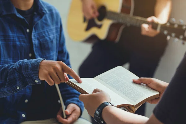 Christian family worship God in home with  playing guitar, and holding holy bible .Group christianity people reading bible together.Concept of wisdom, religion, reading, imagination.